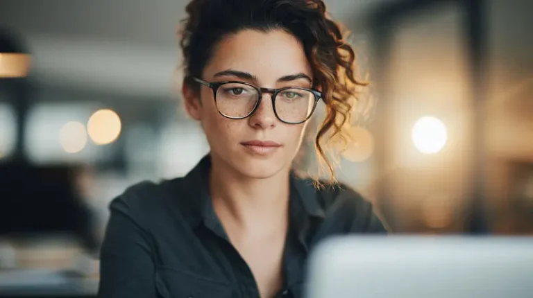 Professional woman sitting alone at her office desk with a forced smile, symbolizing the invisible struggle of mental health